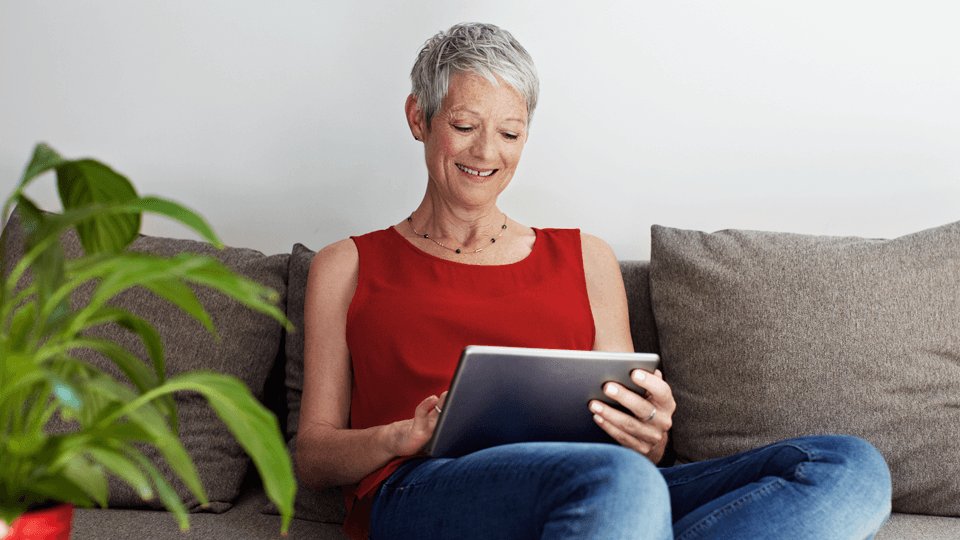 Happy person looking at smart device sitting on sofa