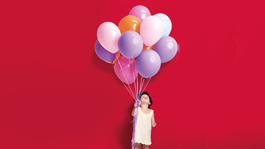 Child holding assortment of ballons